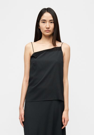 Camisole noire à fines bretelles, ornée d'une bordure en dentelle sur un côté. Tissu lisse et léger avec un design asymétrique.