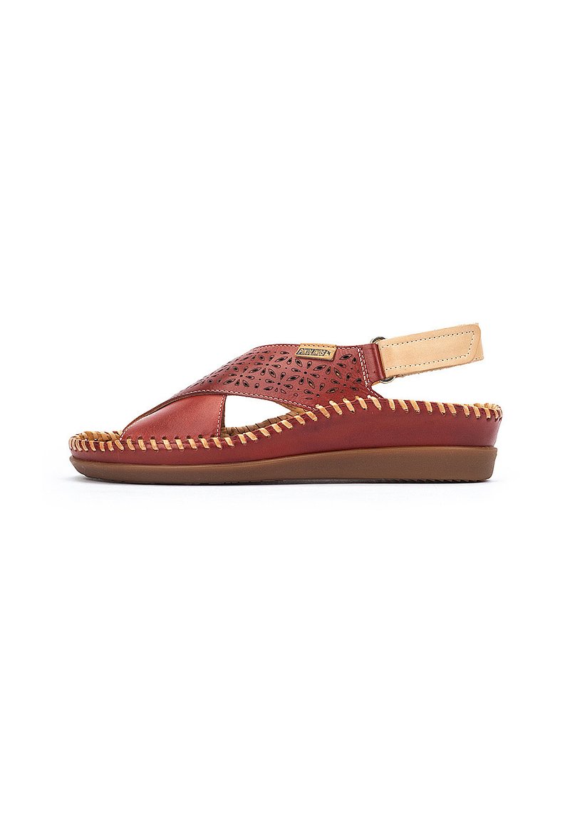 Sandal de cuero rojo con patrones recortados, diseño de tiras para el talón y acentos beige. Suela texturizada con costuras decorativas a lo largo del borde.
