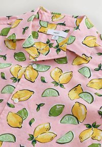 Camisa de manga corta en rosa claro con un patrón de limones y limas, con botones blancos y un diseño con cuello, fabricada en tela suave.