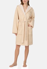 Beżowy szlafrok z kapturem, o miękkiej teksturze, z dwoma przednimi kieszeniami, paskiem do wiązania i subtelnym haftem na piersi.