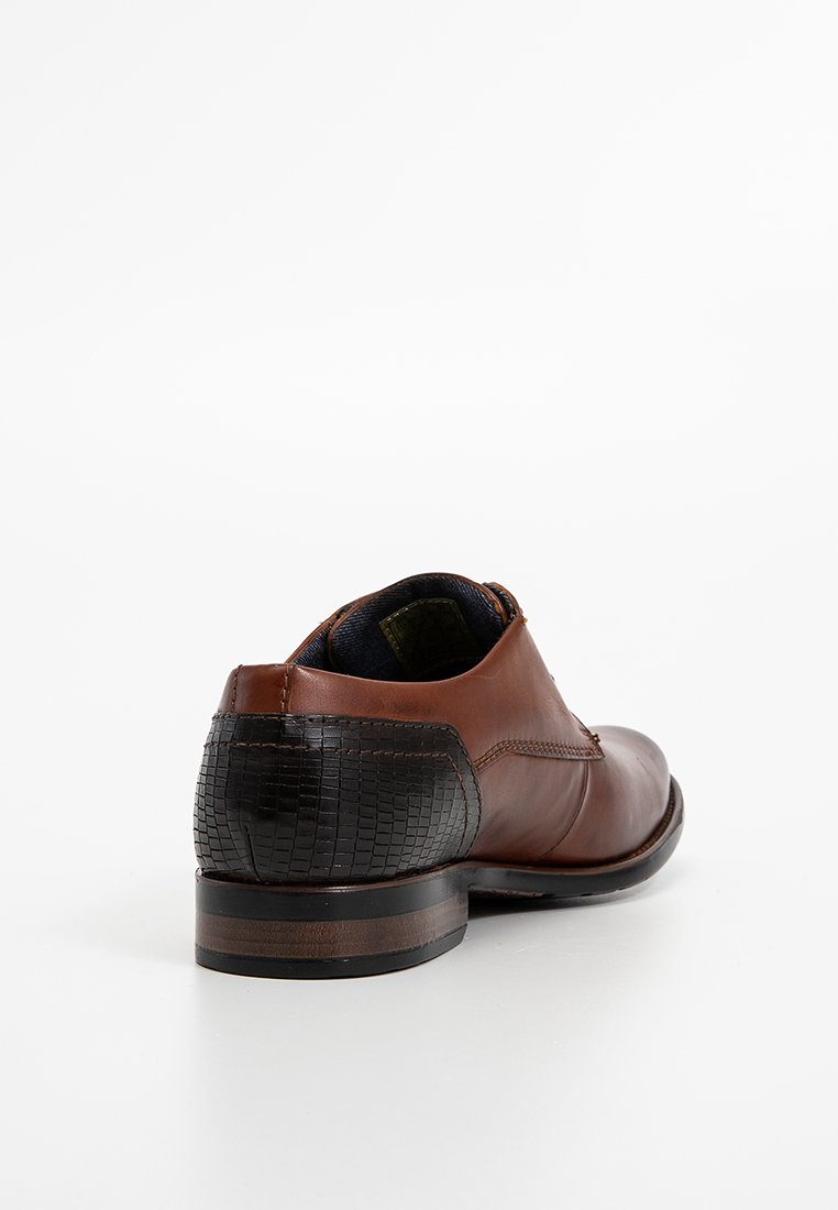 Braunes Leder-Oxford-Schuh mit schwarzem strukturiertem Fersenkappen, niedrigem Blockabsatz und Steppdetails, fotografiert auf weißem Hintergrund.