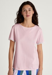 Lichtroze t-shirt met korte mouwen en een ronde halslijn, voorzien van kantafwerking op de mouwen, gemaakt van zachte katoen.