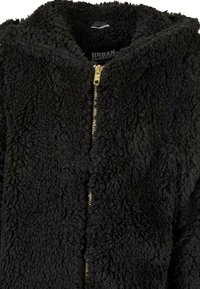 Svart fluffy hettejakke med teksturert stoff, med en gullglidelås og innvendig etikett. Enkelt design uten ytterligere detaljer.