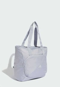 Bolso tote de tela color gris claro, con asas dobles, un bolsillo delantero con cremallera y un logo sutil. Textura lisa y diseño minimalista.