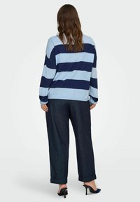 Blue and navy striped sweater made of soft knit material, paired with dark blue wide-leg jeans, and black heeled shoes.