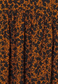 Kangas bermotif bunga dalam warna oranye dan hitam, menampilkan lipatan dan detail menggumpal di bagian atas. Teksturnya terlihat lembut dan ringan.