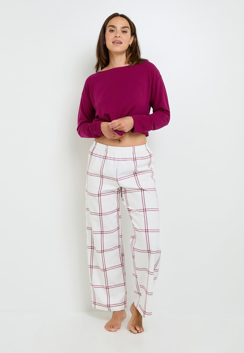 Haut à manches longues cropped bordeaux associé à un pantalon large à carreaux blanc avec des motifs de grille rouges ; matériau en coton doux ; coupe décontractée.