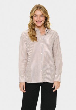 Camisa de cuadros en beige claro y tonos de óxido apagados, con un bolsillo en el pecho y mangas largas con puños abotonados.