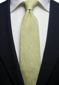 Musta puku vaaleanharmaan paidan kanssa ja tekstuurilla varustettu vaaleanvihreä solmio, jossa on vino kuvio, solmittuna kaulaan.