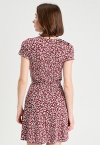 Robe bordeaux à manches courtes avec un motif floral, taille cintrée et jupe évasée, fabriquée en tissu léger et texturé.