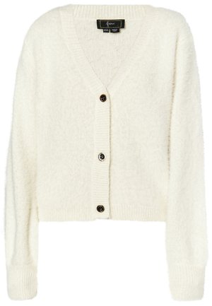 Balts, īss kardigans no pūkainas auduma. Tam ir dziļš V veida kakls, ribotas piedurknes un trīs melnas pogas priekšpusē.