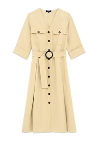 Abito beige con scollo a V, maniche a tre quarti, due tasche sul petto, chiusura con bottoni neri e una cintura coordinata con fibbia rotonda.
