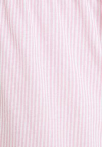 Ljust rosa tyg med vita vertikala ränder, med en mjuk, texturerad yta. Ränderna är jämnt fördelade och fina.