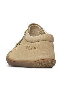 Krémová semišová bota s kulatou špičkou, zelenými tkaničkami a strukturovanou gumovou podrážkou. Obsahuje šité detaily a jemně embosované logo na patě.