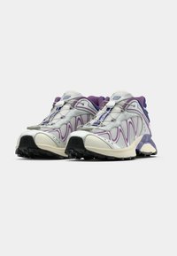 Silver and purple sneakers with a mesh upper, rubber sole, curved design, and prominent lacing system.  Textured accents and cushioned collar.