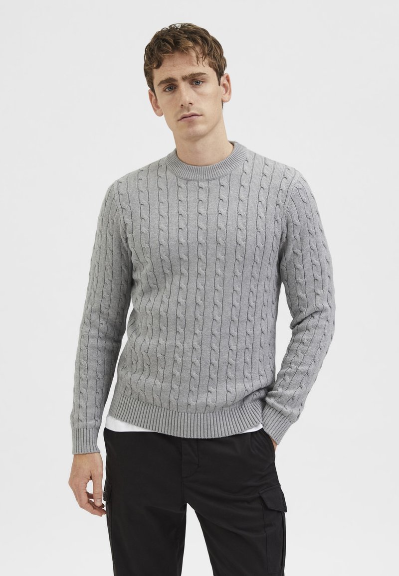 Suéter de punto trenzado en gris claro con cuello redondo y puños y dobladillo acanalados. La tela tiene un aspecto texturizado.