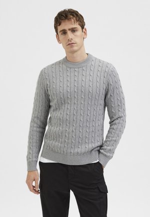 Hellgrauer Kabelstrickpullover mit Rundhalsausschnitt sowie gerippten Bündchen und Saum. Der Stoff hat eine strukturierte Optik.