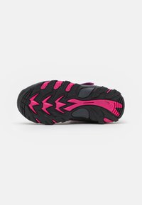 Trail shoe sole featuring a black rubber base with pink accents and textured tread for grip. Includes grooves and a curved design for flexibility.