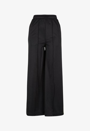 Schwarze weit geschnittene Hose mit elastischem Bund, glattem Stoff und sichtbaren Nahtdetails. Hat eine lockere, fließende Silhouette.