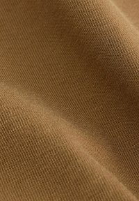 Brūns teksturēts audums ar smalku rievojumu; materiāls izskatās mīksts un elastīgs, parādot siltu, neitrālu toni.
