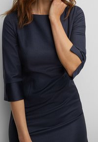 Robe bleu marine avec des manches trois-quarts, un motif à carreaux texturé et une silhouette ajustée, confectionnée dans un matériau lisse.