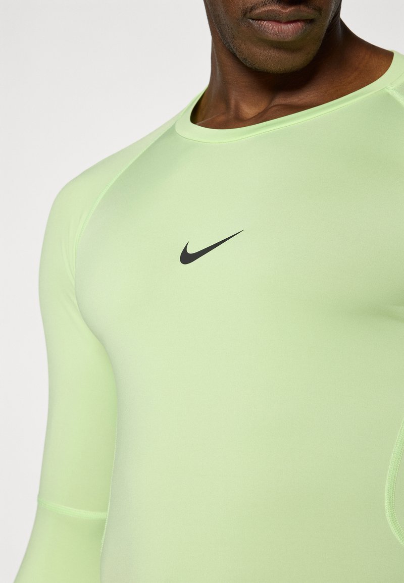 Hellgrünes langärmliges Sportshirt aus dehnbarem Stoff mit schwarzem Nike-Logo auf der Brust und gerippten Details an den Bündchen.