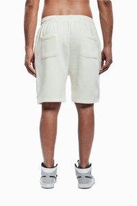 Hvite bomullsshorts med snøring i midjen, med to baklommer. Modellen har på seg grå og hvite joggesko.