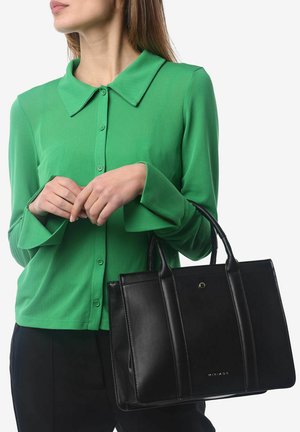Sac fourre-tout en cuir noir avec un design structuré, une finition brillante et deux anses supérieures. Associé à une chemise à manches longues verte à boutons.