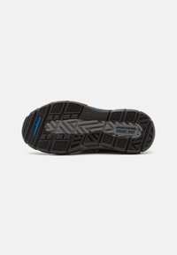 Black athletic shoe sole with textured grip patterns, featuring a blue accent and the words "GoodYear" and "Steady Grip" on the side.