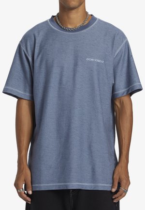 Kortærmet blå t-shirt lavet af tekstureret stof, med rund hals og syede detaljer, hvor logoet vises i hvidt foran.