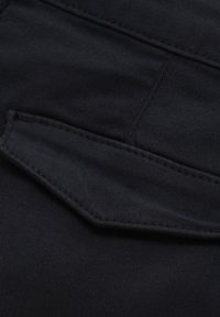 Svart texturerad tyg med en sydd fickdetalj, som visar upp släta linjer och en strukturerad design med en matt finish.