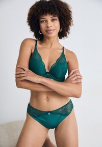 Teal kant bh en bijpassende slip, met ingewikkelde bloempatronen, verstelbare bandjes en een kleine decoratieve accent aan de voorkant.