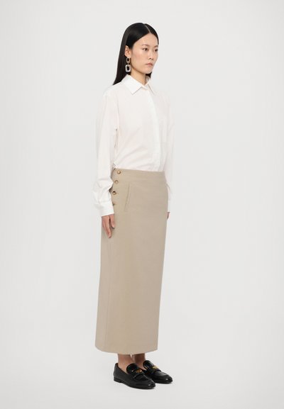 Hvid skjorte med knapper, beige midi nederdel med sidelukninger, flade sorte loafers. Enkelt design, blødt materiale, lige silhuet.