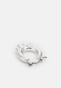 Brinco de argola prateado em forma de mão, com uma textura lisa e brilhante e um fecho articulado para uso seguro.