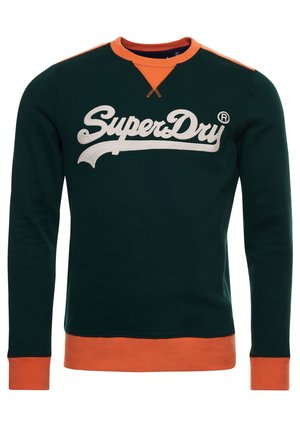 Ciemnozielona bluza z pomarańczowym kołnierzem, mankietami i dołem, z dużym białym napisem "SuperDry" na piersi.
