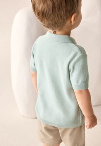 Heleroheline kootud polosärk lühikeste varrukatega, soonikkoes mansettide ja kraega, kombineeritud khaki lühikeste pükstega.