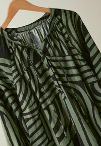 Blusa verde e nera con motivo a strisce allungate, colletto rotondo e sei bottoni sul davanti. Realizzata in tessuto leggero.