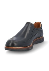 Zapato negro de cuero tipo mocasín con paneles elásticos laterales, punta redonda y suela marrón contrastante. Textura suave y mínimos detalles de costura.