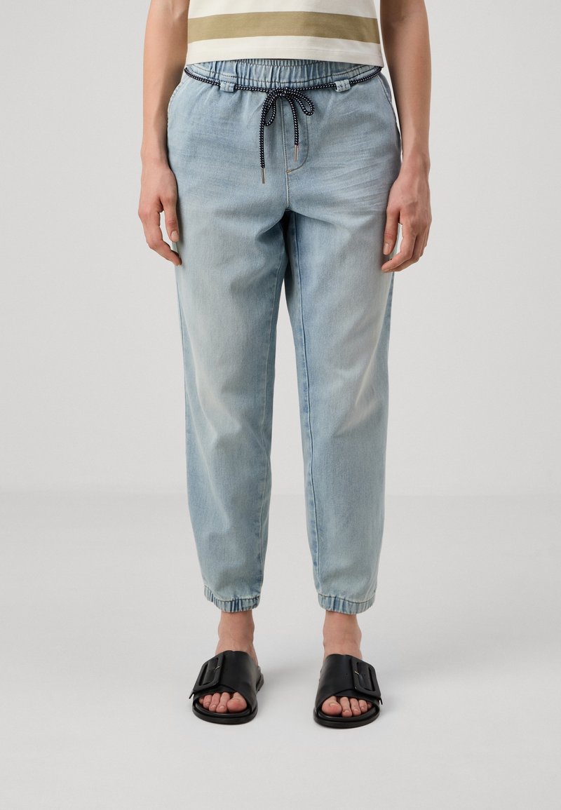 Ljusblå denim joggerbyxor med elastisk midja, justerbar dragsko och ribbade muddar. I kombination med svarta slip-on sandaler.