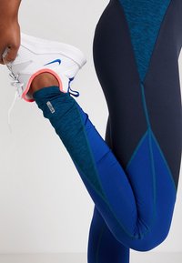 Leggings sportivi blu con pannelli bloccati nei colori navy e teal, con un design aderente e texture a rete nella zona dei polpacci.