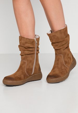 Braune Wildleder-Ankle Boots mit einer lässigen Form, seitlichem Reißverschluss und strukturiertem Gummisohle. Mit gesteppten Details und einem weichen Innenfutter.