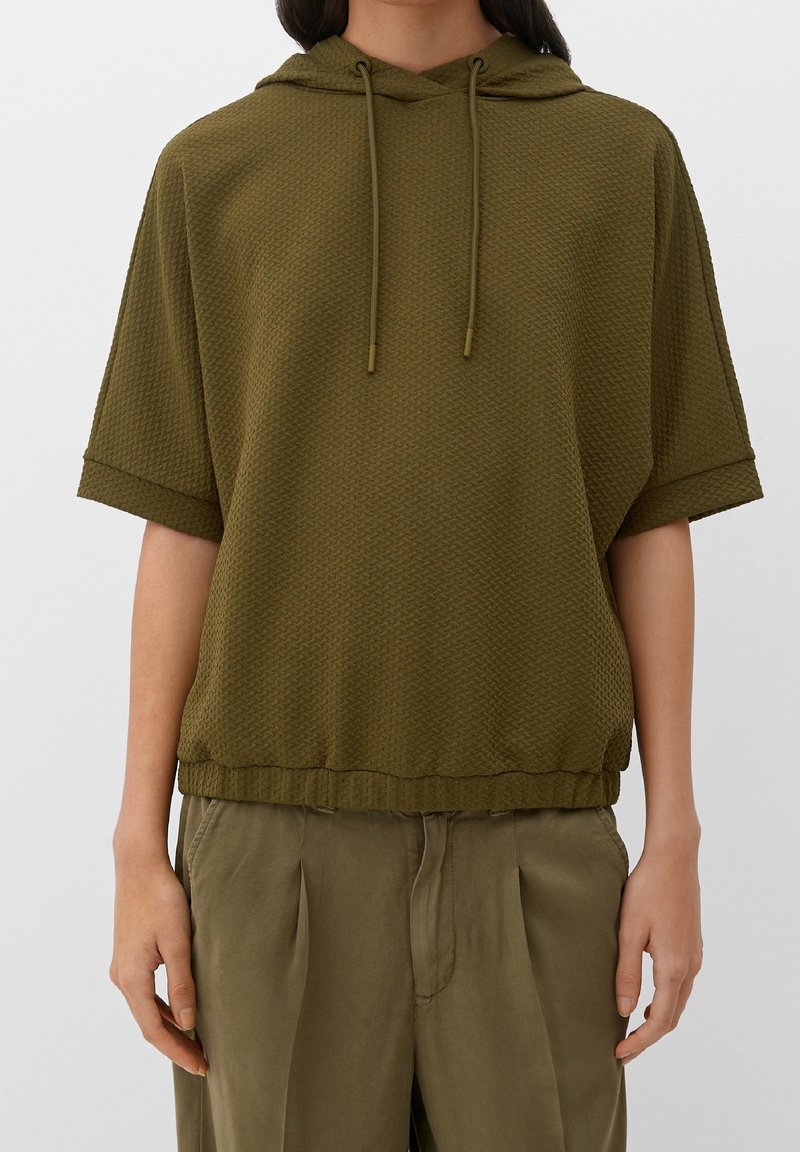 Sudadera con capucha de color verde olivo en tejido texturizado, con mangas cortas, cordón ajustable y un dobladillo que queda justo por encima de la cintura.