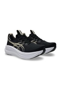 Svarta atletiska skor med texturerad ovandel, vit mellansula och gyllene detaljer. Har snören, strömlinjeformad form och kontrasterande sula.