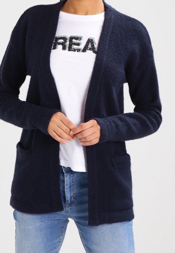 Navyblauer Cardigan aus weichem, strukturiertem Stoff, mit offenem Vorderteil, langen Ärmeln und zwei vorderen Taschen, getragen über einem weißen Hemd.