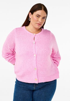 Lyserød strikket cardigan med rund halsudskæring, fem knapper og ribstrikkede manchetter. Blød tekstur og afslappet pasform, parret med mørkeblå jeans.