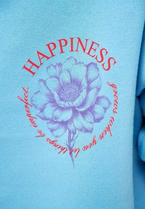 Niebieska tkanina z ilustracją fioletowego kwiatu oraz czerwonym napisem „HAPPINESS” i „grace deepens your let things be imperfect” wokół niego.