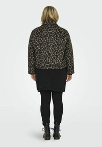 Leopardi kuviollinen takki ruskeana ja mustana, jossa on kauluksellinen kaulus, rento istuvuus ja pehmeä rakenne, yhdistetty mustan paidan ja legginssien kanssa.
