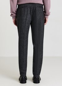 Pantaloni neri con texture e taglio dritto, caratterizzati da due tasche posteriori e una sottile lucentezza, abbinati a scarpe nere lucide.