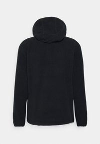 Felpa con cappuccio in pile nero dalla texture morbida, maniche lunghe e cappuccio arrotondato. La parte posteriore presenta un design liscio e senza interruzioni.