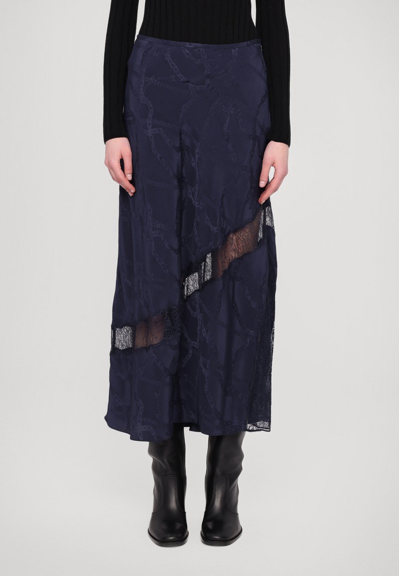 Marineblaue Rock mit Spitzenakzenten, asymmetrischem Design, strukturiertem Muster und transparentem Einsatz, kombiniert mit schwarzen Knöchelstiefeln.